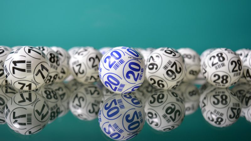 A row of numbered lottery balls lined up against a teal background